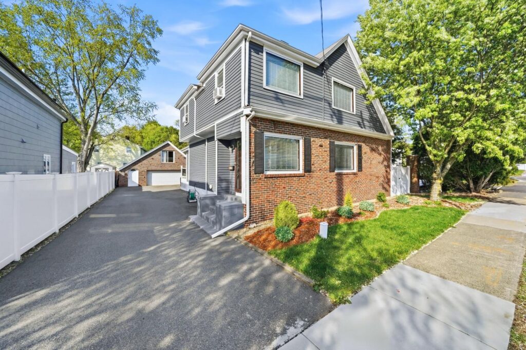 Side exterior of a two-story home with driveway and front landscaping.